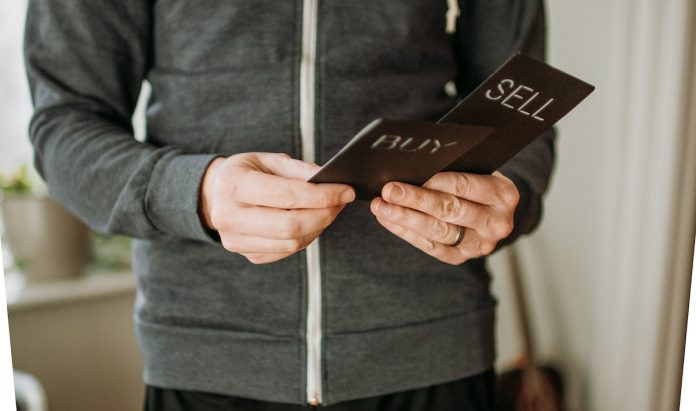 Man looking at two cards that say buy or sell