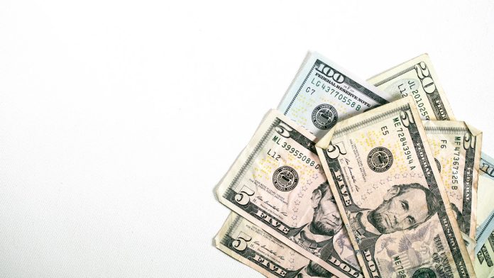 A small pile of USD / American Dollar Bills fanned out nicely in the corner of a simple white background.