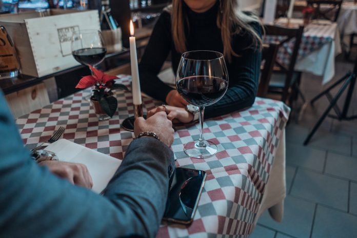 man on a date holding hands with a girl at a table at a restaurant